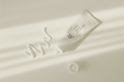 A white tube of cream from Beauty of Joseon with its cap off lies on a sunlit surface. Cream is artistically squeezed out in a wavy line next to the tube.