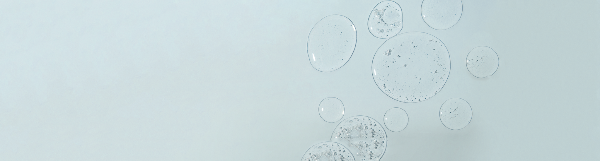 Transparent gel serum textured bubbles float on a soft blue background.