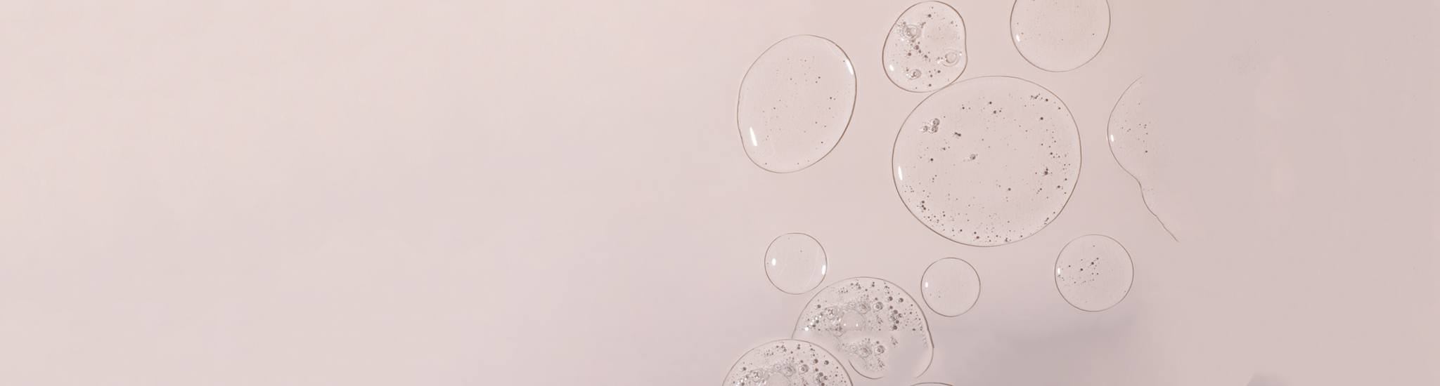 Transparent gel serum textured bubbles float on a soft pink background.