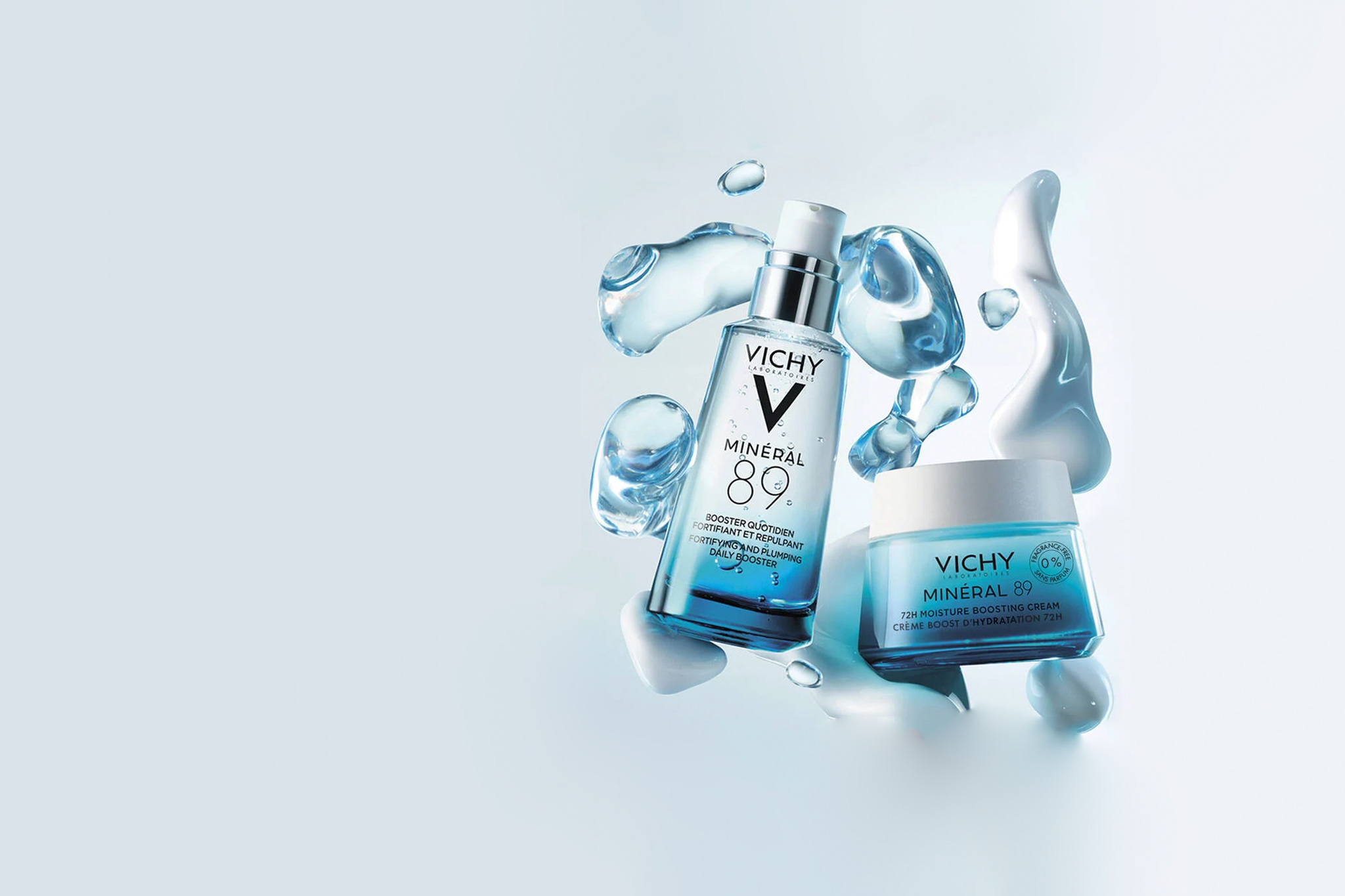 A Vichy skincare set featuring a bottle of Mineral 89 booster serum and a jar of Mineral 89 moisturizer, surrounded by water splashes on a light blue background.