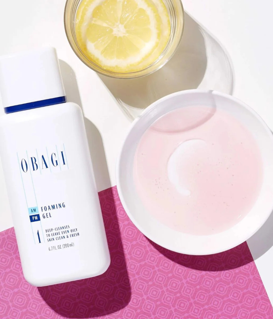 Obagi foaming gel bottle with a bowl of pink cream and a lemon slice on a patterned surface